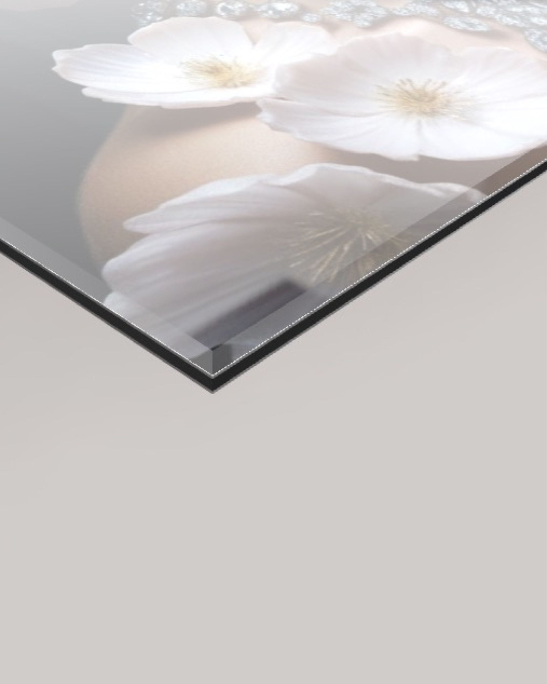 A close-up of a 4mm rectangular glass panel or mirror with a glossy finish, showing a reflection of white flowers and a soft beige background. The glass has a thin dark edge and is photographed at an angle against a light gray background.