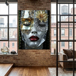 A large wall art print depicting a stylized grey marble face with a gold flower, diamond eye lids, and red lips, displayed on a brick wall in a modern loft-style room with windows and wood floors. 