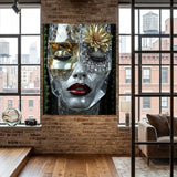 A large wall art print depicting a stylized grey marble face with a gold flower, diamond eye lids, and red lips, displayed on a brick wall in a modern loft-style room with windows and wood floors. 