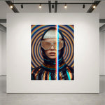 A large wall-mounted artwork in a gallery setting, showing a stylized portrait split vertically with a red-blue light dividing the frame. The artwork features a hooded figure with metallic visor-style glasses against concentric circular patterns in blue, orange, and black.