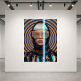 A large wall-mounted artwork in a gallery setting, showing a stylized portrait split vertically with a red-blue light dividing the frame. The artwork features a hooded figure with metallic visor-style glasses against concentric circular patterns in blue, orange, and black.