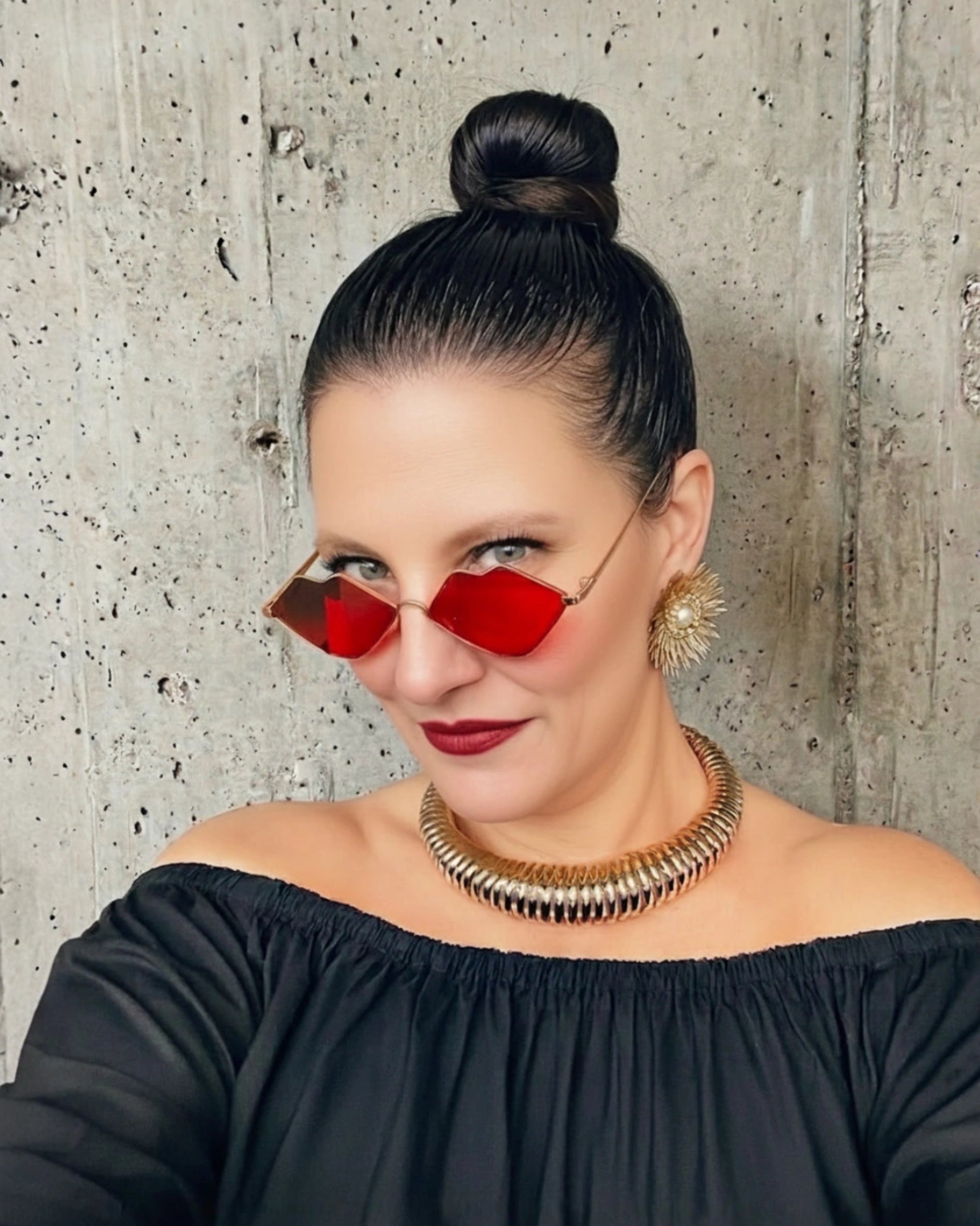 MizDragonfly founder Karine Eyamie wearing signature bold fashion jewelry, including a sculptural gold collar and lip-shaped eyewear, in her Toronto studio.
