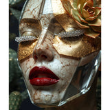 A close-up of a sculptural face mask with a cracked skin-like texture, red glossy lips, glittery diamond eyelashes, and a gold succulent flower on the side, set against a cacti background. 