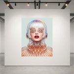 A large square wall art print displayed on a white gallery wall, featuring a stylized portrait of a woman with silver hair, metallic mesh sunglasses, and a reflective geometric collar against a pale blue background. The print is shown in a modern gallery space with track lighting and concrete floors.