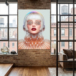 A large vertical wall art print featuring a surreal portrait of a woman with a metallic, wire-like head and glowing red lips, displayed on a brick wall in a modern loft room with wood floors and large windows.