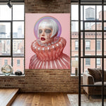 A large vertical artwork displayed in an acrylic glass frame featuring a stylized portrait of a woman with platinum white hair, a pink background, and a glossy pink ruffled collar, displayed on a brick wall in a modern loft room with windows and a sofa.