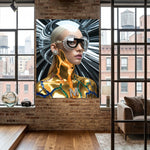 A large square wall art print featuring a stylized futuristic woman with platinum blonde hair, dramatic black crystal sunglasses, and a metallic gold body armour, displayed on a brick wall in a modern loft room with wood floors and large windows.
