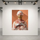 A surreal art print displayed on a large white gallery wall, featuring a figure in a white head covering and clear plastic jacket with exposed pink and gold anatomical details against an orange background.
