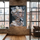 A large framed wall art print featuring a stylized portrait of a woman with triangular glass headpiece adorned with pink flowers, diamond earrings and necklace, displayed on a brick wall in a modern loft interior with wood floors and large windows.