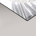 A close-up of a glossy rectangular panel with a reflective silver surface and a black edge, shown against a light gray background.