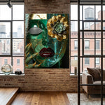 A large canvas wall art print featuring a stylized green glass face with gold leaf textures, a succulent flower, and red lips, displayed on a brick wall in a modern loft room with wood floors and windows.