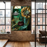 A large canvas wall art print featuring a stylized green glass face with gold leaf textures, a succulent flower, and red lips, displayed on a brick wall in a modern loft room with wood floors and windows.