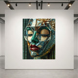 A large canvas art print depicting a stylized, green and gold woman face with gold glitter details and red lips, displayed on a white gallery wall in a modern art studio.